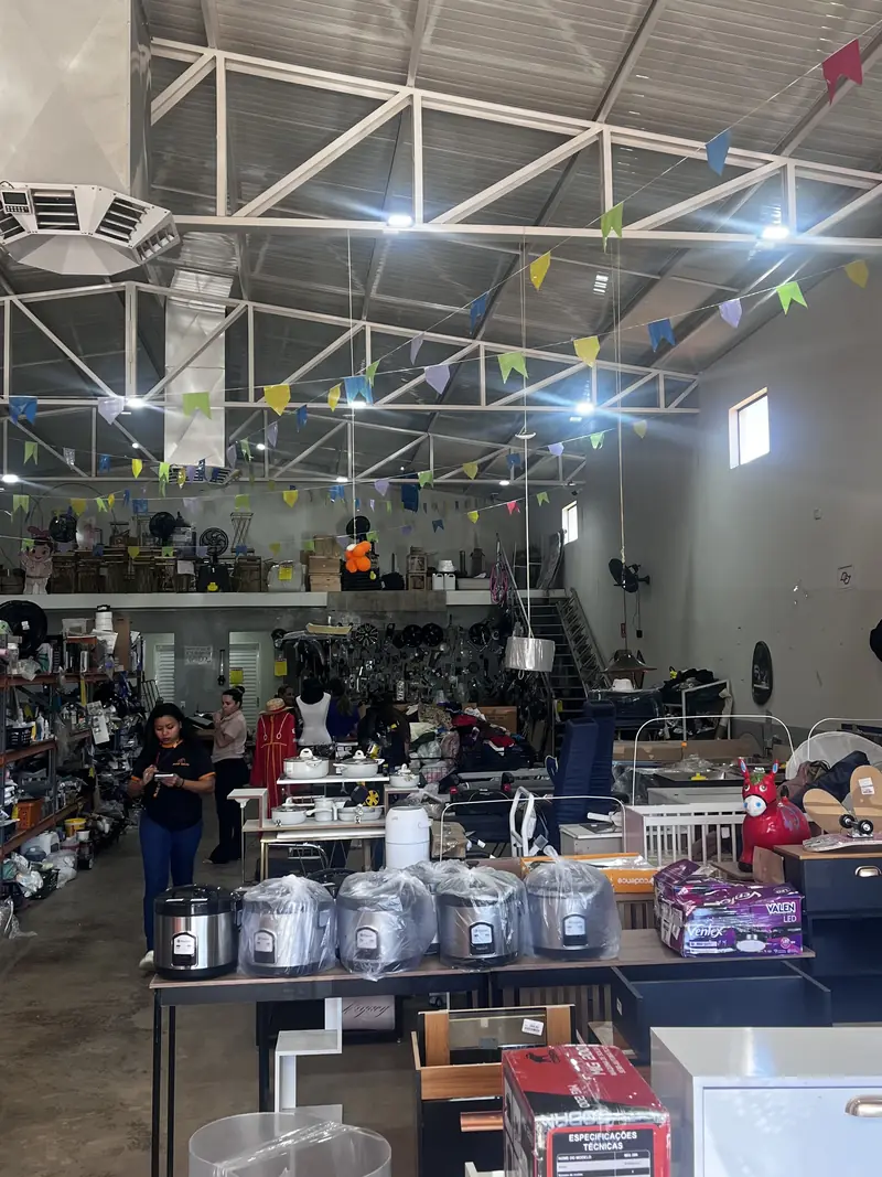 Vista geral do salão da loja, com bandeirinhas no teto, panelas e eletroportáteis nas mesas